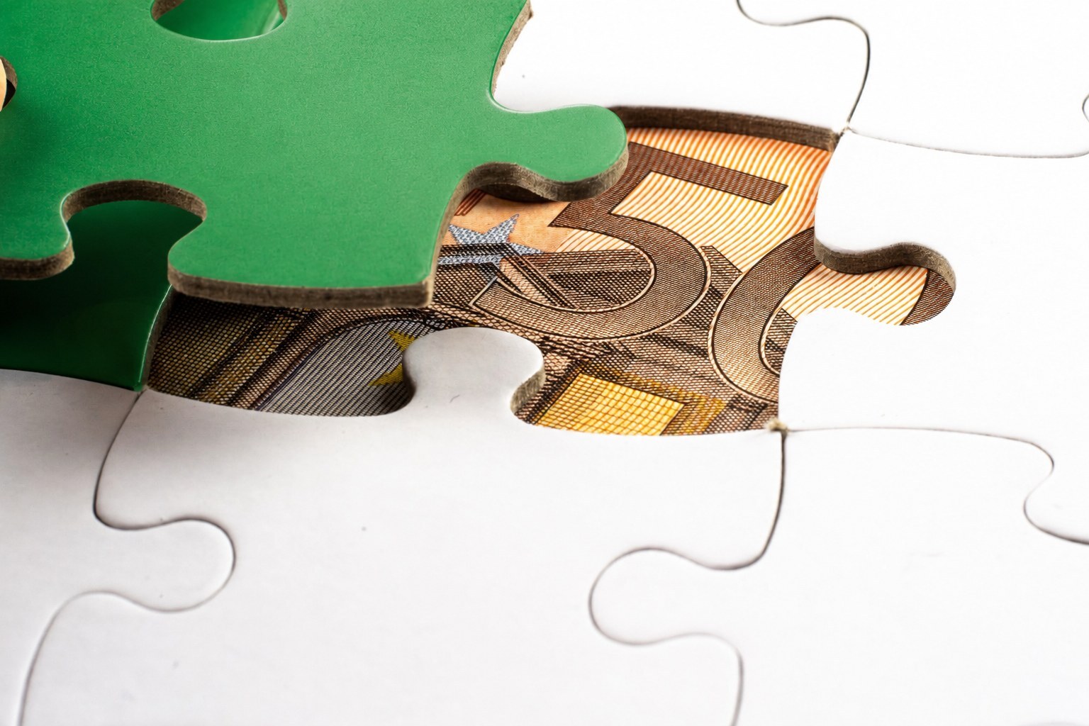 Puzzle: das grüne Teil ist angehoben, darunter liegt ein 50-Euro-Schein